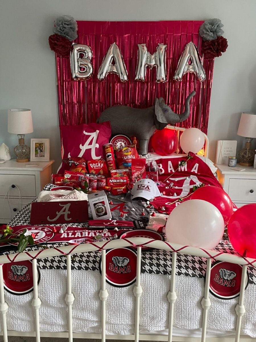 Alabama bed party with BAMA balloon letters, red streamers, elephant plush, and extensive Crimson Tide merchandise