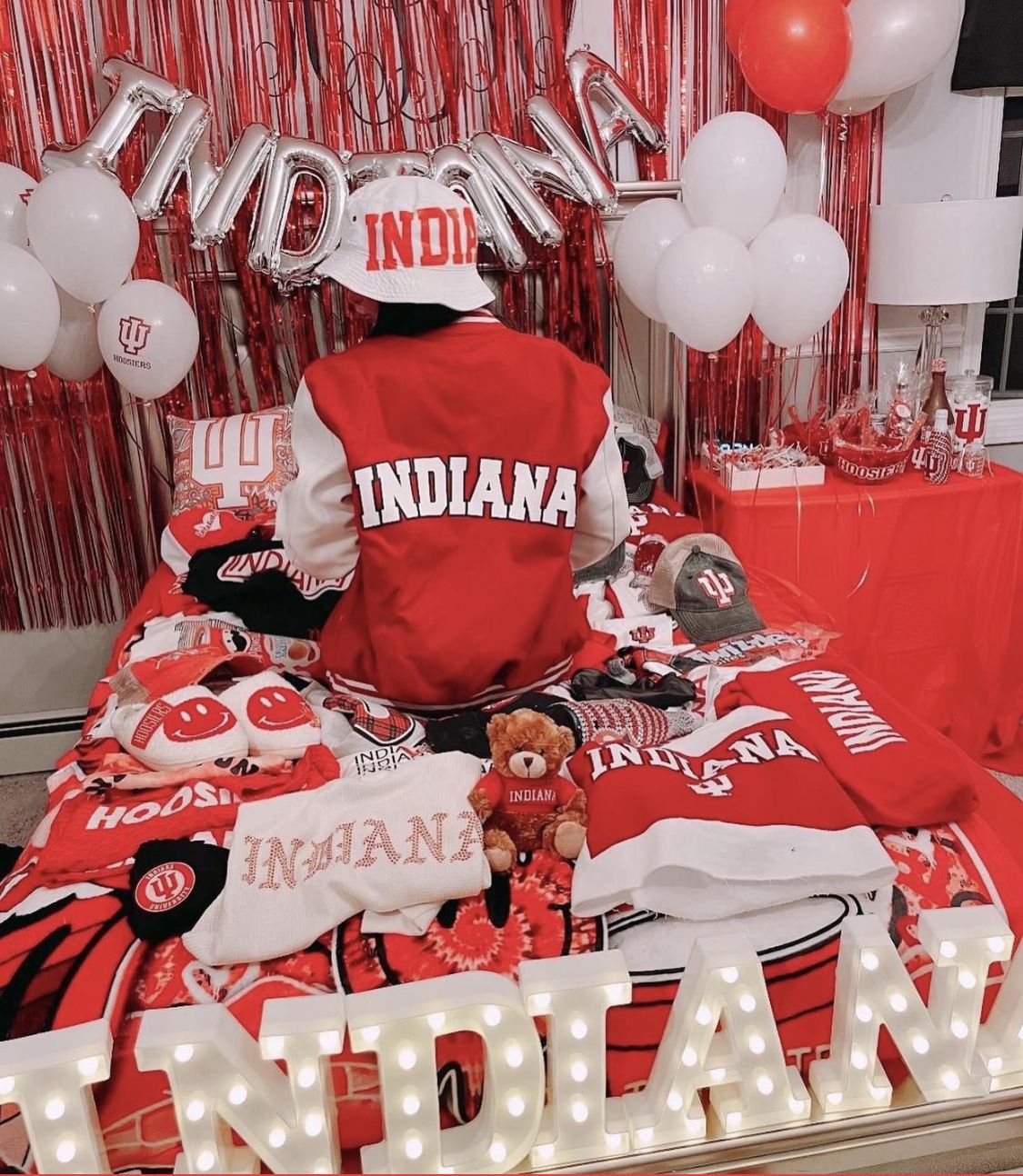 Indiana bed party with INDIANA balloon letters, red streamers, and IU Hoosiers merchandise display