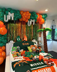 University of Miami bed party with UM balloon letters, green and orange decorations, and Hurricanes merchandise