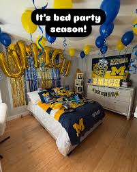 Michigan bed party with 'It's bed party season!' sign, maize and blue balloons, and Michigan Wolverines merchandise