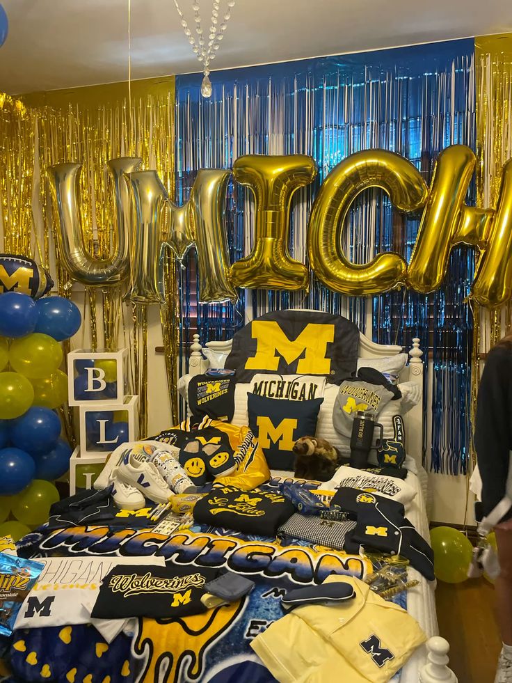 University of Michigan bed party with UMICH balloon letters, blue and gold streamers and Wolverines merchandise