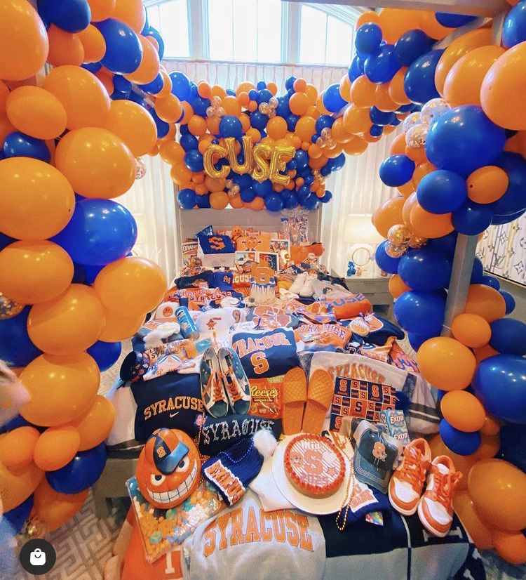 Syracuse bed party with CUSE balloon letters, massive orange and blue balloon arch, and extensive Orange merchandise
