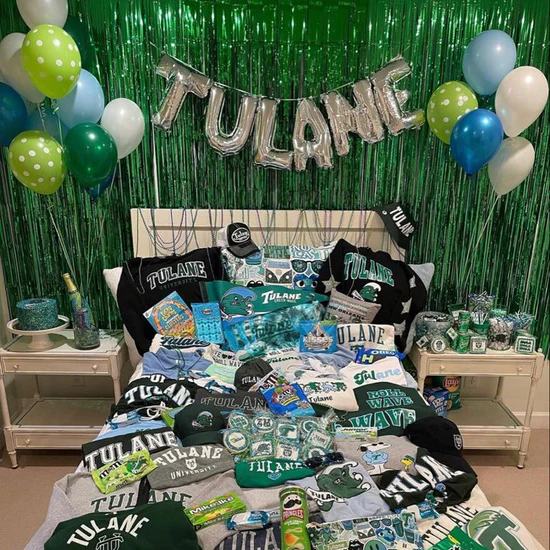 Tulane bed party with TULANE balloon letters, green streamers, and Green Wave merchandise collection
