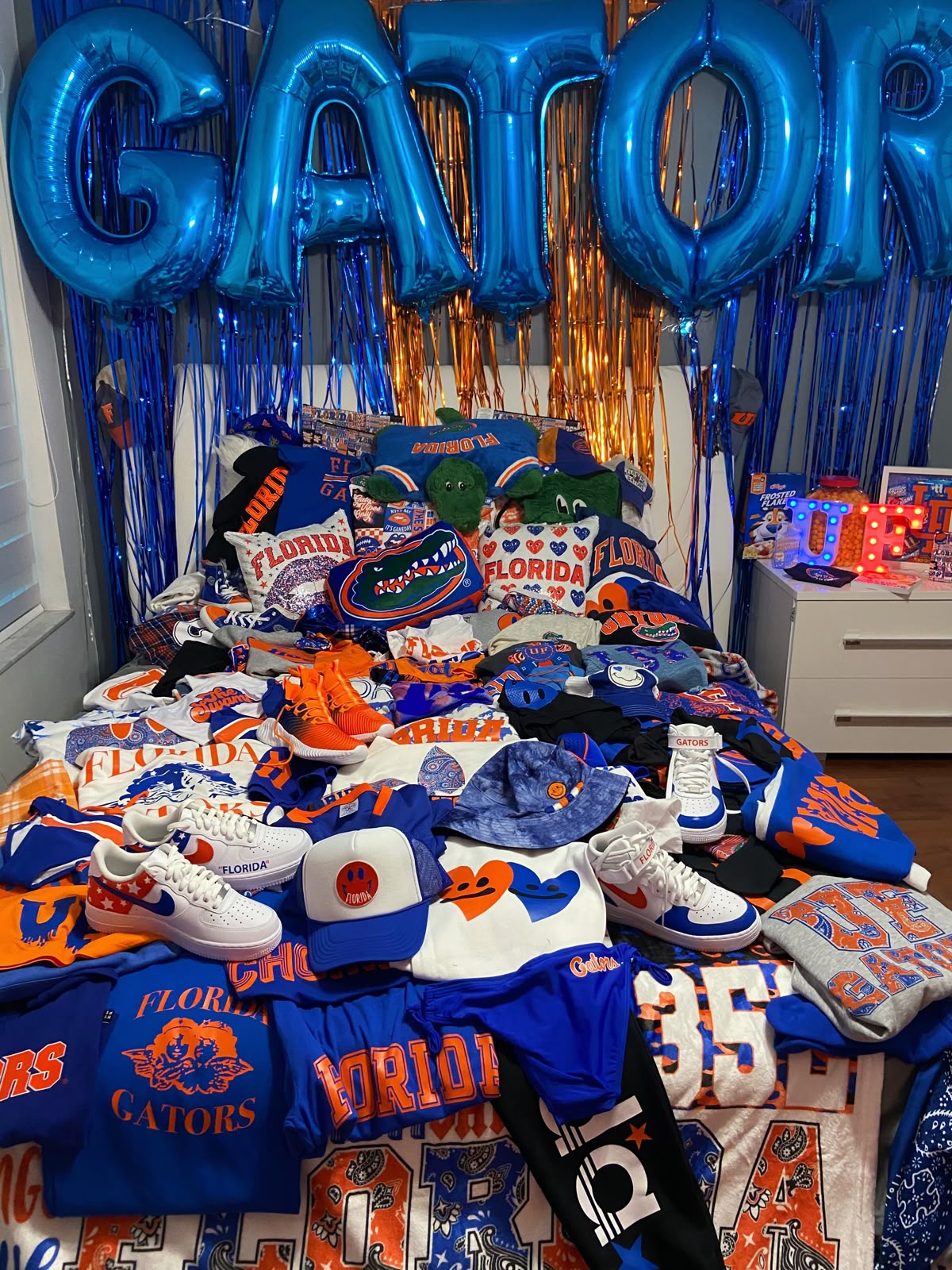 Florida Gators bed party with massive GATOR balloon letters, blue and orange streamers, and extensive UF merchandise collection