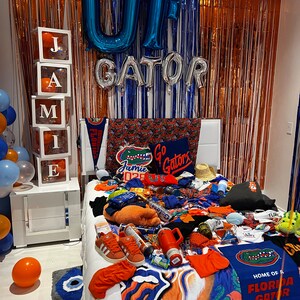 University of Florida bed party with UF GATOR balloon letters, blue and orange streamers